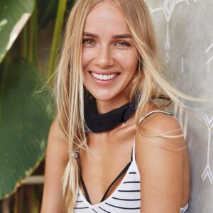 Bandana 100% personalizzabile ambiant 3 Happy young cute female student glad to have summer holidays after hard year of studying, has glad expression and attractive appearance, poses against grey wall with green plant in background